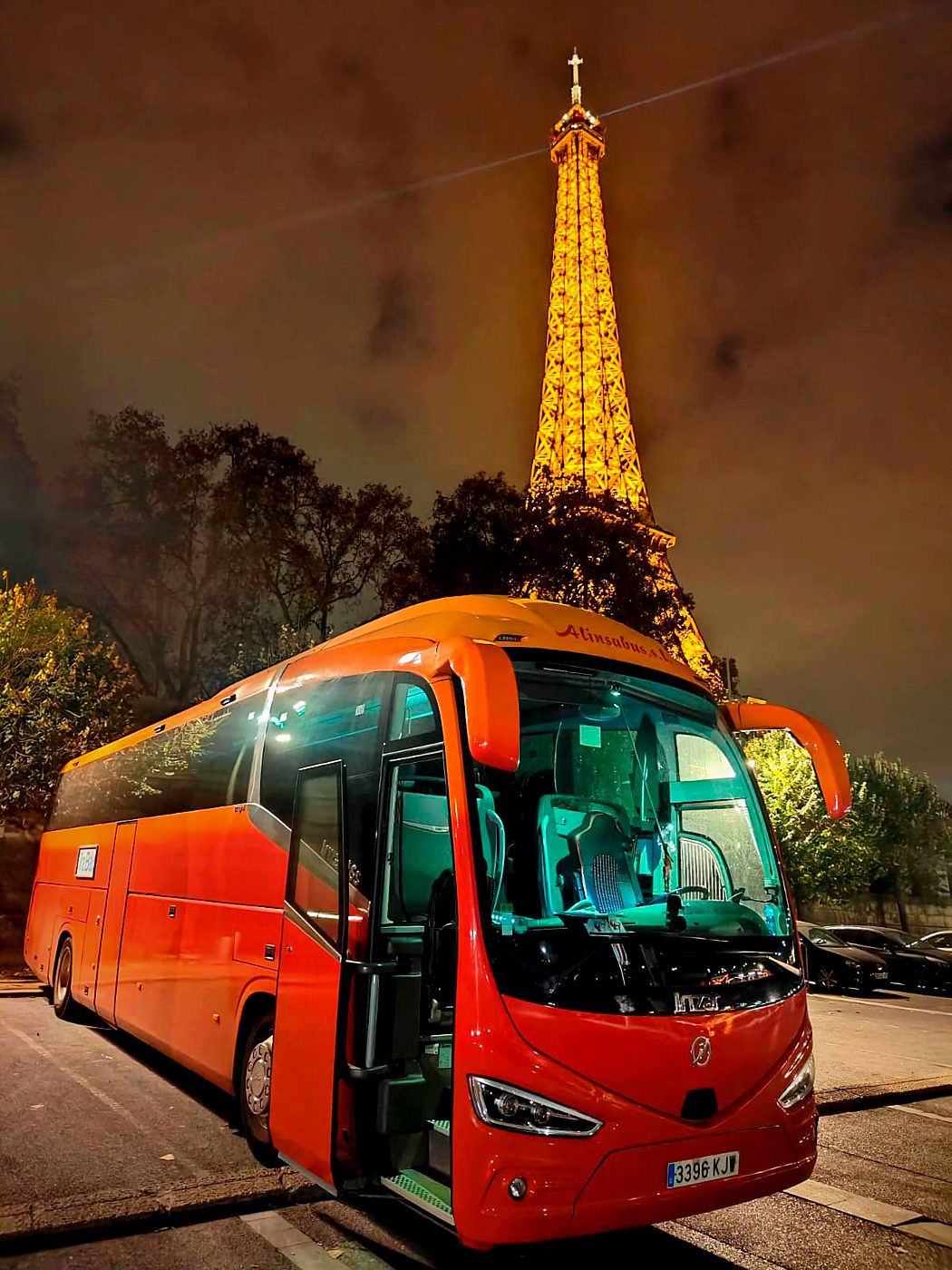 Autocar de Kapital Bus ante la Torre Eiffel iluminada, en París
