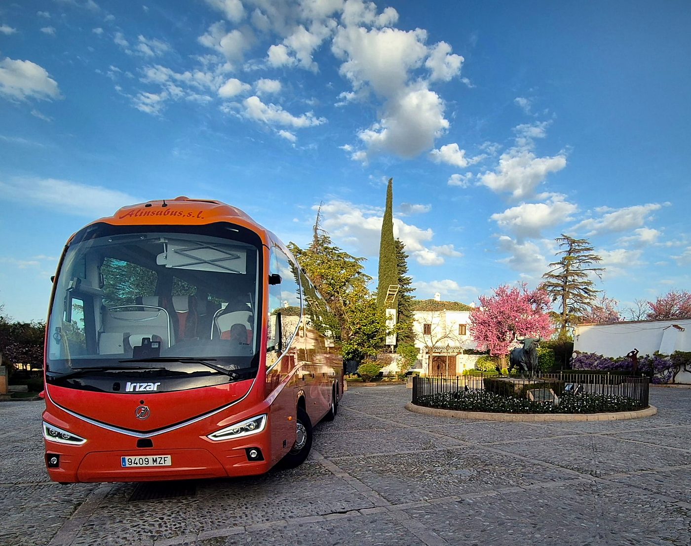 Autocar de Kapital Bus en una plaza con almendros en flor